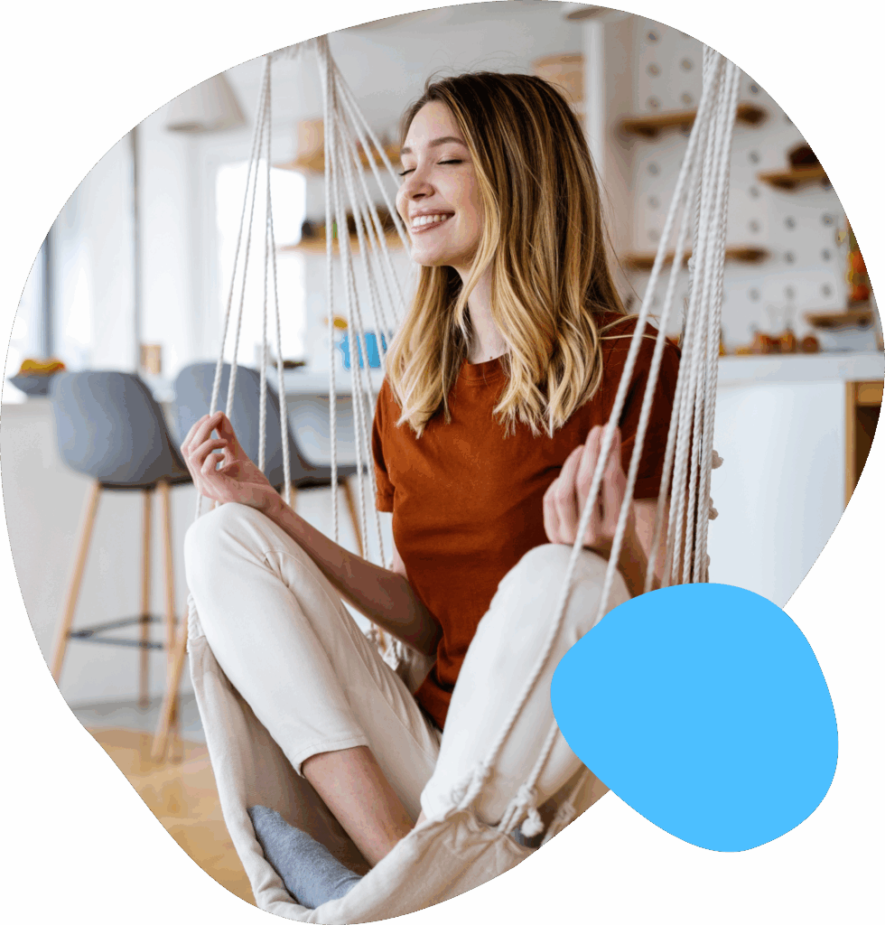 A young woman sat in crossed legged in a hanging swing chair with her eyes closed